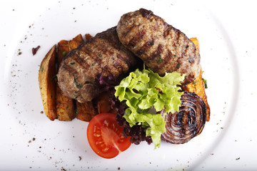 dish with meat, potatoes and herbs on a white plate