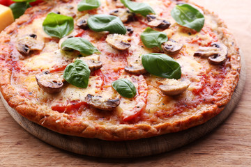 Tasty pizza with vegetables and basil on table close up