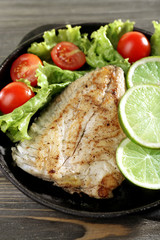 Dish of fish fillet with salad and lime on table close up