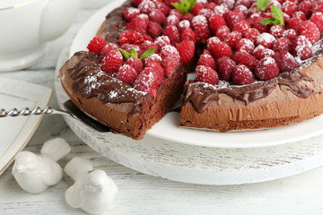 Piece of cake with chocolate Glaze and raspberries on color wooden background