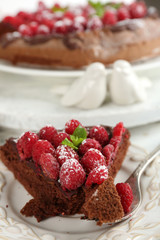 Piece of cake with chocolate Glaze and raspberries on color wooden background