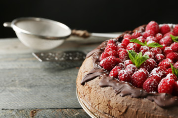 Cake with Chocolate Glaze and raspberries on tray on dark background