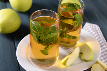 Glasses of apple juice with fruits and fresh mint on table close up