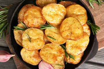Delicious baked potato with rosemary in frying pan on table close up