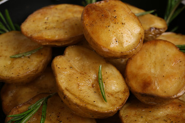 Delicious baked potato with rosemary in frying pan close up