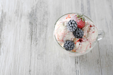 Delicious ice cream with fresh frozen berries, on color wooden background