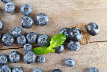 Tasty ripe blueberries with green leaves on wooden table close up