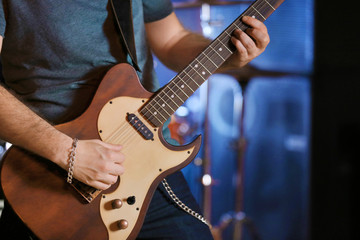 Fototapeta premium Young man playing on electric guitar close up