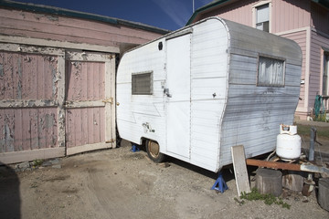 Fototapeta na wymiar White beatup trailer parked in front of pink garage, Ventura, California, USA, 01.29.2014
