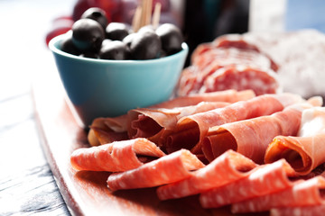 Charcuterie assortment and black olives on wooden background