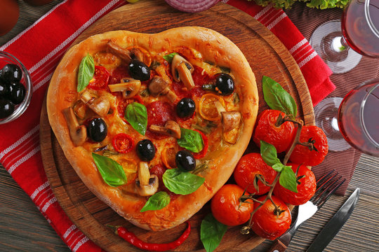 Heart shaped pizza served on wooden table closeup