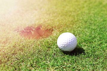 Golf ball on lip of cup on the green golf course