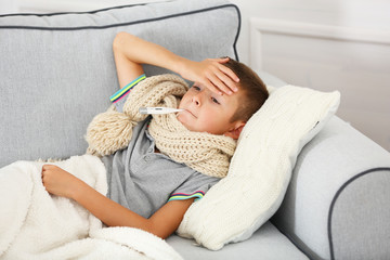 Sick boy with cold sitting on sofa