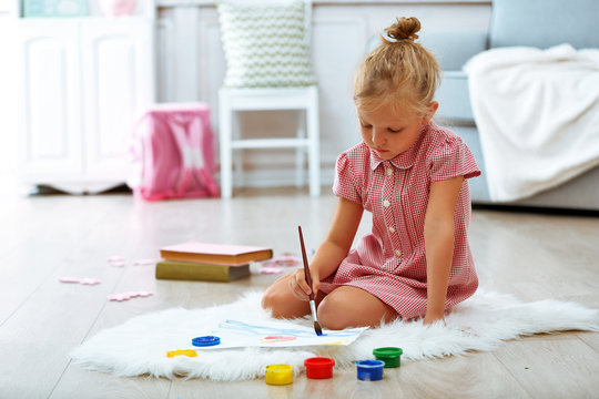Little girl drawing in the room