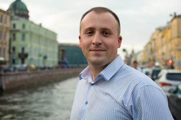 A man dressed in a nice shirt. It stands on the background of the river.
