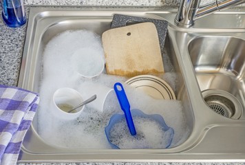 Fototapeta na wymiar Dirty dishes in soapy water in a kitchen sink