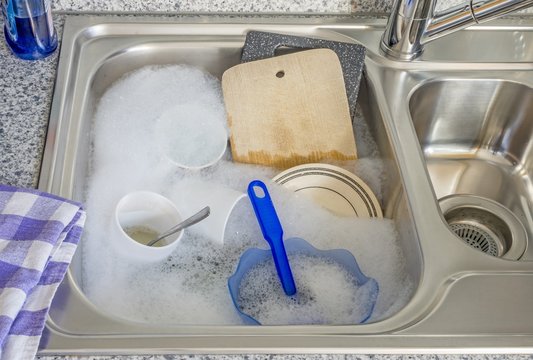 Dirty Dishes In Soapy Water In A Kitchen Sink