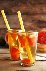 Iced tea with lemon and grapefruit on wooden background