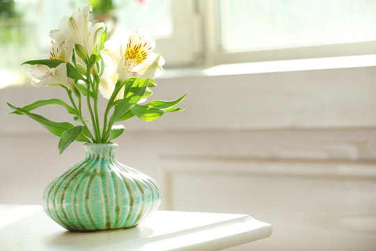 Beautiful Alstroemeria flowers in aquamarine vases on window background