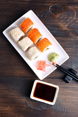 Delicious rolls, ginger, wasabi and soy sauce on wooden background