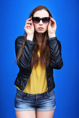 Fashionable young woman posing outdoor over blue wall