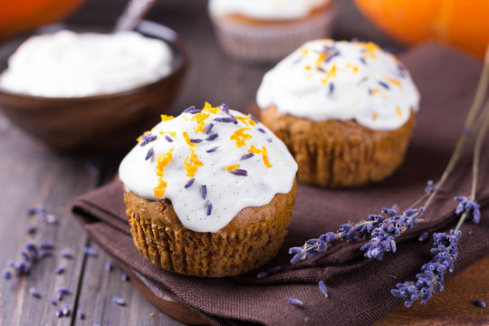 Sweet pumpkin cupcake with cream cheese icing decorated with lavender, selective focus