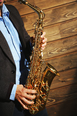Obraz premium The musician with sax on wooden background, close up