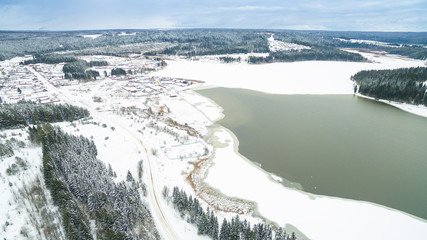 winter aerial photo of the river, forests, village and grey sky