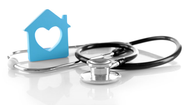 Concept of family medicine - blue plastic house with heart shaped window and stethoscope isolated on white background
