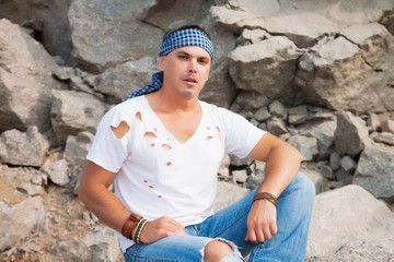 Attractive man sitting on a rock in the mountains