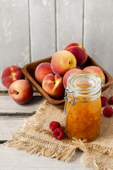 Peach jam and bowl of peaches on rustic wooden table
