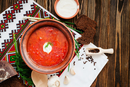
Ukrainian national cuisine , red borscht with sour cream , herbs , garlic and rye bread on a wooden background