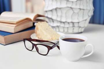 Cup of coffee with books on table in room