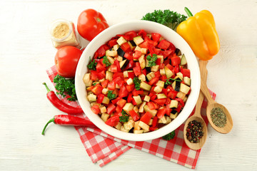 Ratatouille before cooking and ingredients, on wooden background