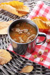 Mug of soup on wicker mat closeup