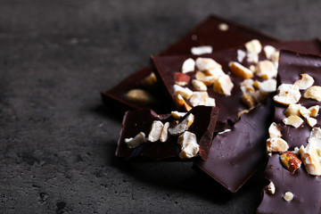 Black chocolate pieces and nuts on dark gray background