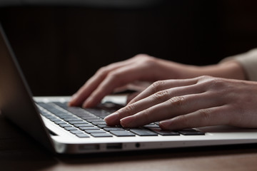 woman hands using laptop at office desk, with copyspace in dark