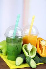 Fresh vegetable juices on color wooden table, on bright background