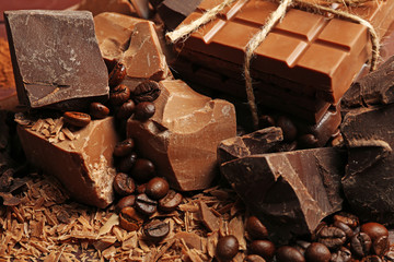 Variety of chocolate pieces, coffee grains and cocoa powder on wooden background
