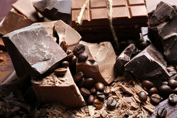 Variety of chocolate pieces, coffee grains and cocoa powder on wooden background