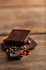 Black chocolate pieces with pepper on wooden background