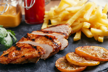 Grilled chicken breast with french fries and sauce