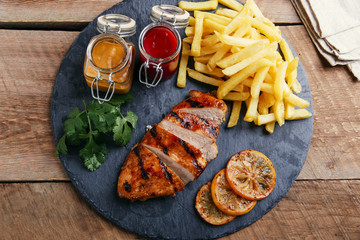 Grilled chicken breast with french fries and sauce