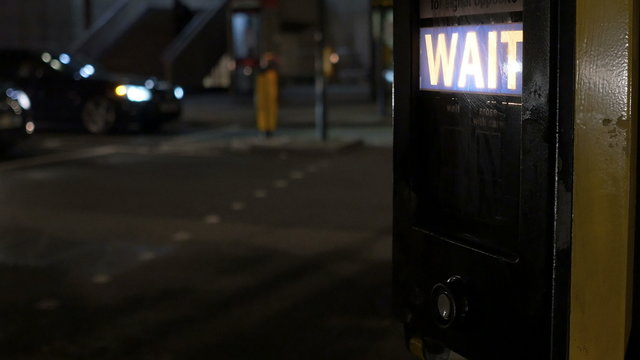Pedestrian is pressing the walking button on walking crossroad in the night, in London city.