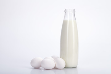 Glass bottle of milk and eggs on a white background