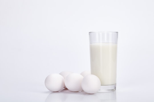 Glass Cup Of Milk And Eggs On A White Background