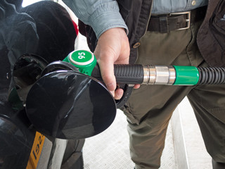 Hand holding fuel pump and refilling car 