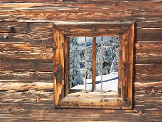Blick durch ein Holzfenster auf den verschneiten Wald