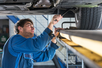 Mechanic examining the suspension of a car during a MOT Test - 94861938