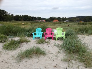 Bunte Plastikstühle am Strand im Sand